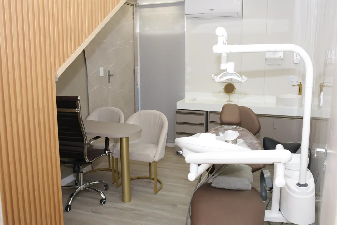 Consultório com mesa para conversa, poltronas e cadeira odontológica