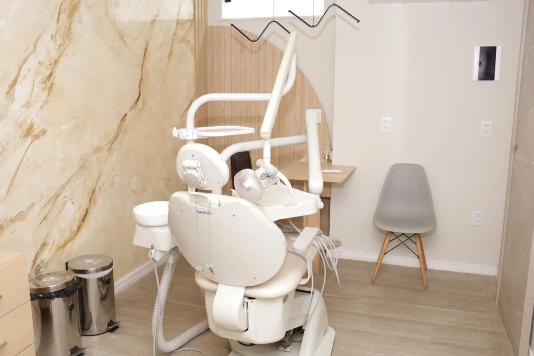 Consultório do COI com cadeira odontológica, parede de pedra e painel de madeira